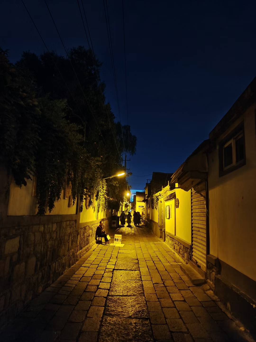 A narrow stone passage lit by warm lamps at night