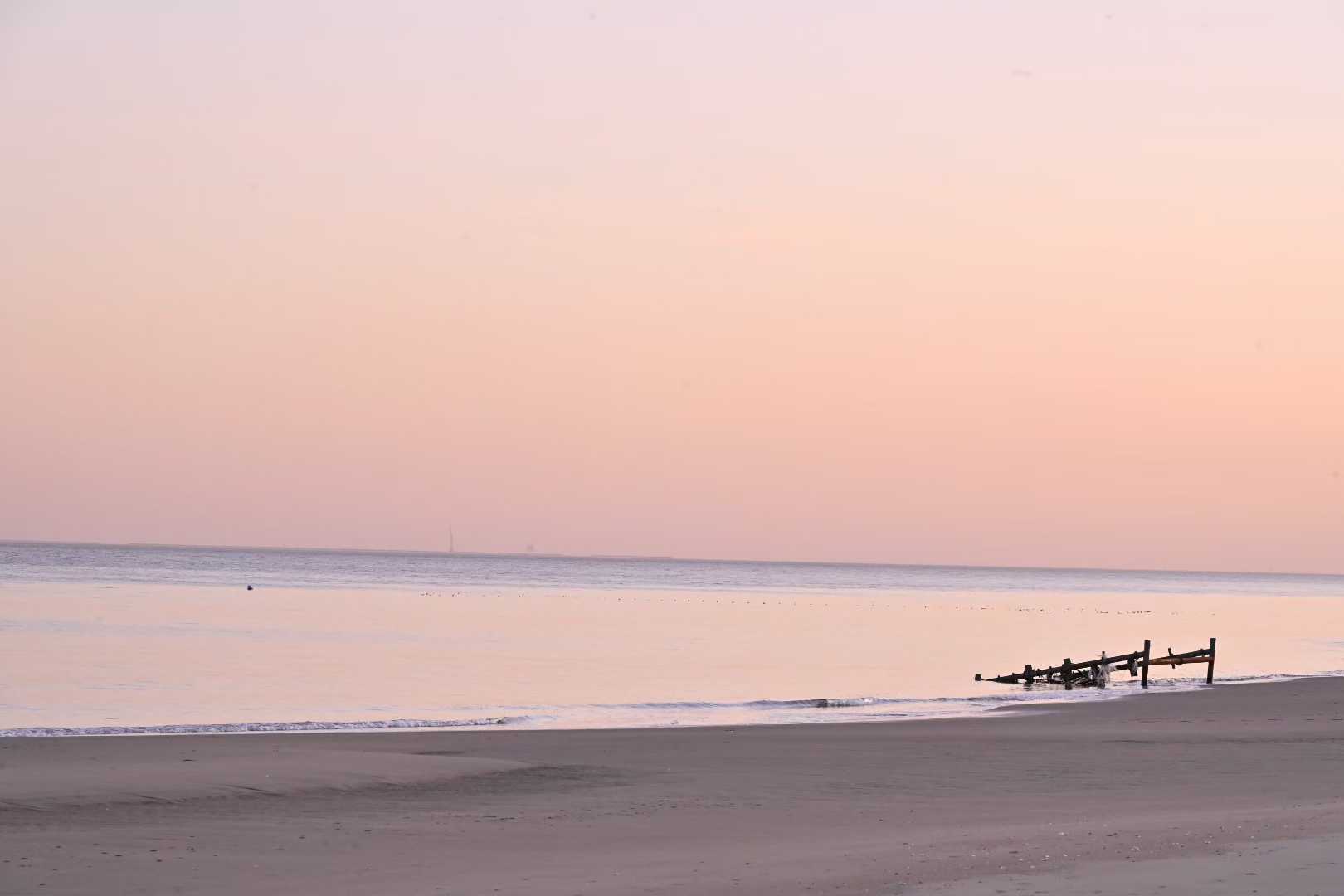 A pale, minimal sea horizon with distant figures