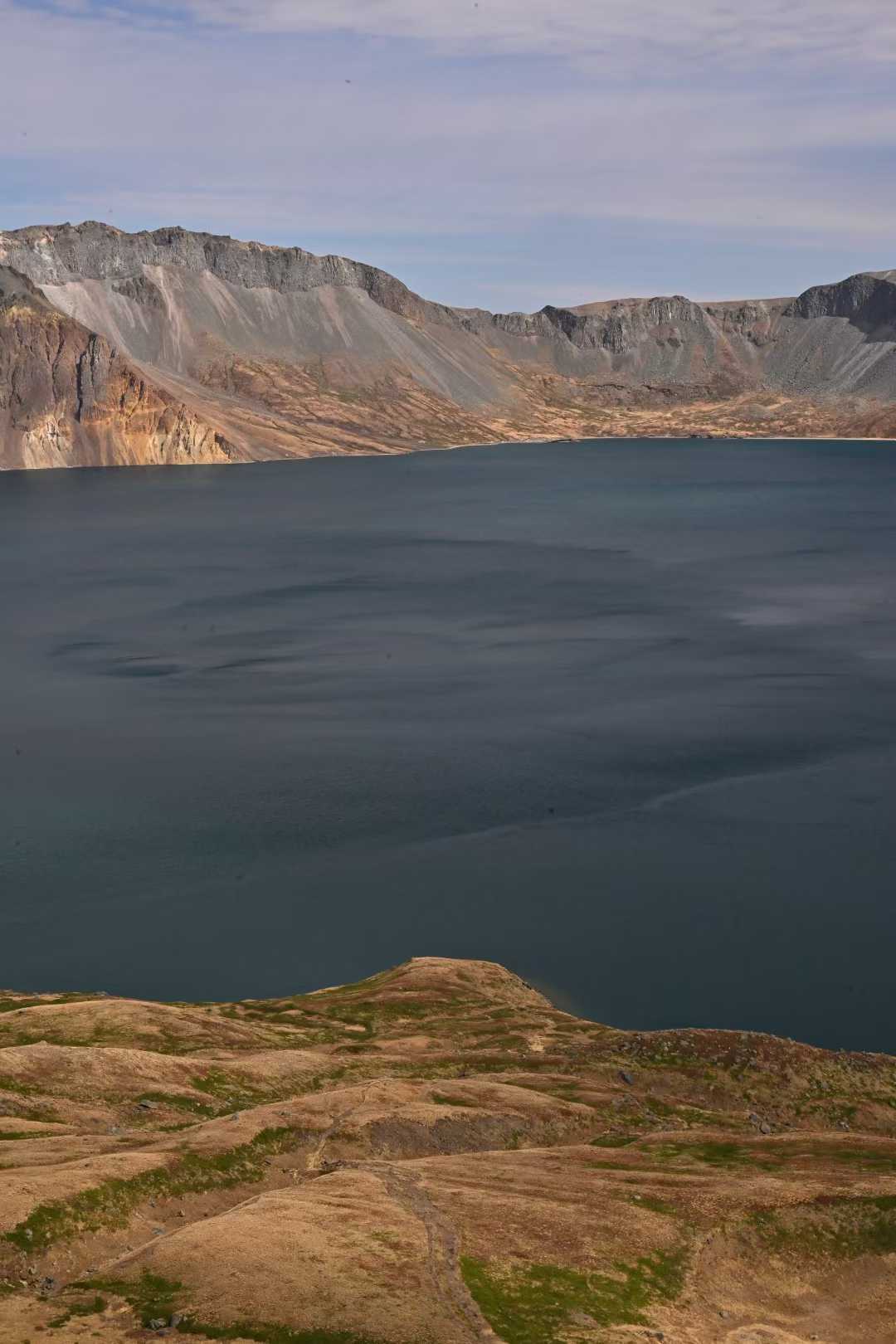 Blue crater lake framed by dark volcanic rock