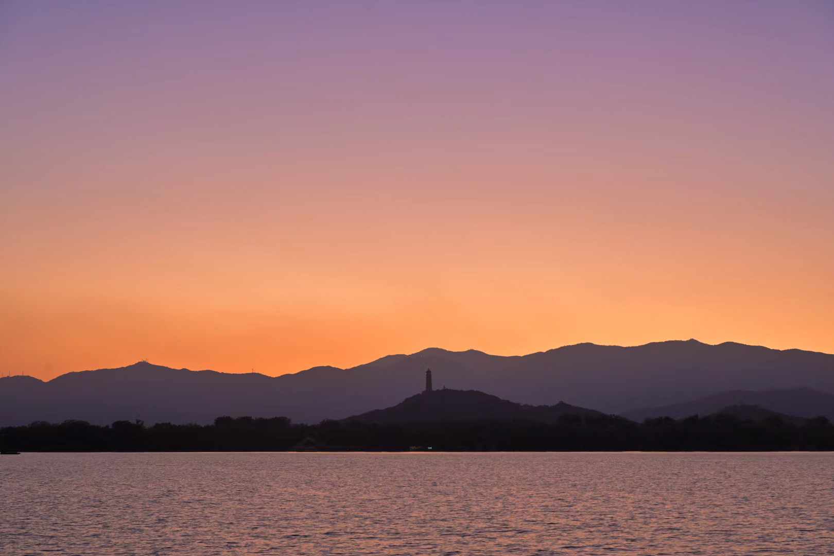 Dark mountain silhouettes under a fading amber sky
