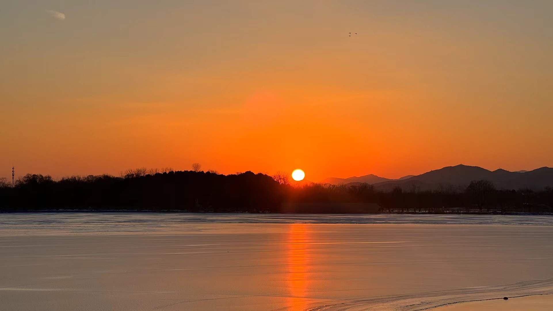 Orange winter sun reflected across a frozen lake
